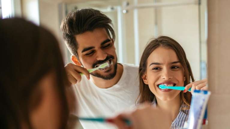 A couple brushes their teeth together, highlighting good periodontal health.